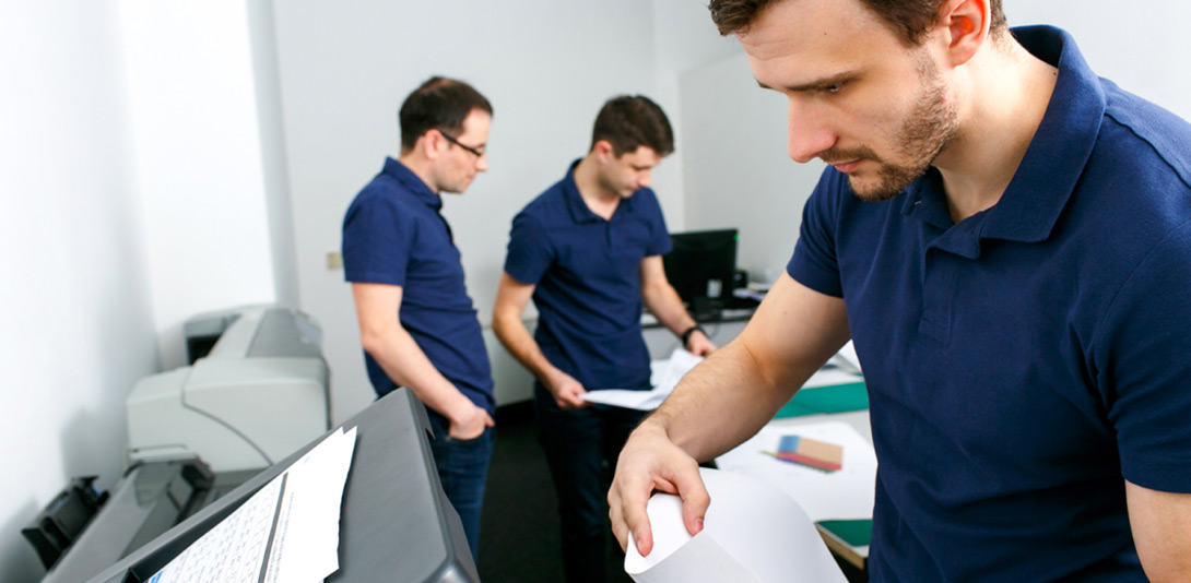 3 homens em um escritório mexendo com impressão